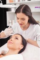 Cheerful female expert beautician is serving her patient photo