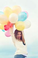 Cheerful young trendy girl with bunch colored balloons photo