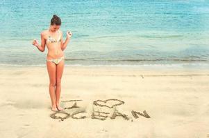 Young cheerful teenage girl writing I love ocean message photo