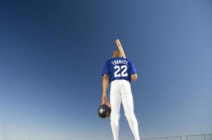 Baseball player against clear blue sky, carrying bat on shoulder photo