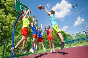 Children jump for ball during basketball game