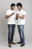 alegre feliz dos hombres jóvenes con smartphone foto
