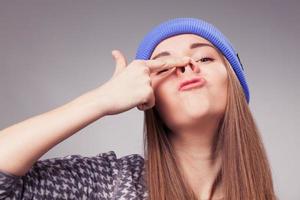 girl holding up fingers on nose and making silly expression