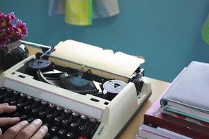 manos escribiendo en una vieja máquina de escribir foto