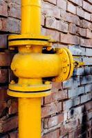 válvula de gas amarilla sobre pared de ladrillo rojo foto