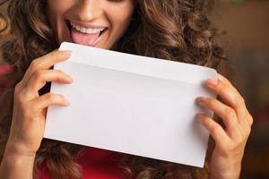 Closeup on happy young woman licking envelope