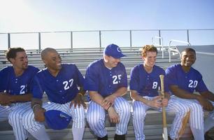 Baseball team on bench in stand during baseball game, (backlit)