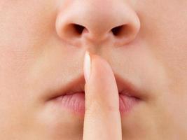 Woman holding finger to lips photo
