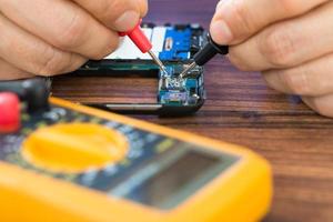 Human Hand  Repairing Cellphone With Multimeter