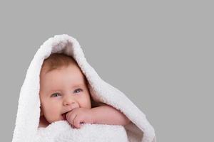 la dentición del bebé muerde la mano con una toalla blanca