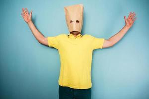 Young man with bag over head and arms raised photo