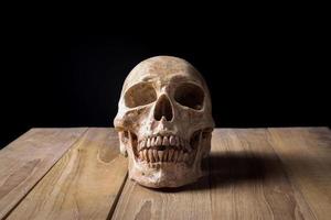 cráneo humano naturaleza muerta en tablero de madera foto