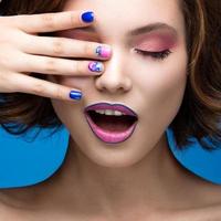 Chica hermosa modelo con maquillaje brillante y esmalte de uñas de colores. foto