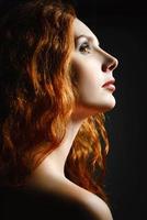 Closeup studio portrait of beautiful redhead woman. Profile view