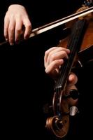 manos femeninas tocar un violín en el negro foto