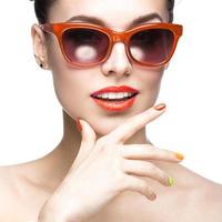 una chica con gafas de sol rojas y uñas coloridas foto