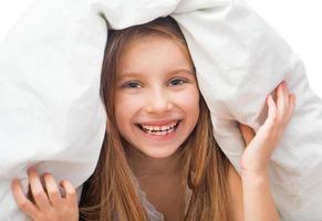 Laughing little girl under a blanket