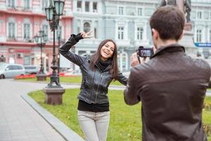 Man making photo of laughing woman outdoors
