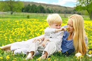 madre y niño pequeño relajante en prado de flores foto
