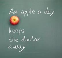 An apple on a chalkboard with an apple a day saying
