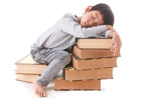 Chico lindo asiático sentado y durmiendo en la pila de libros.