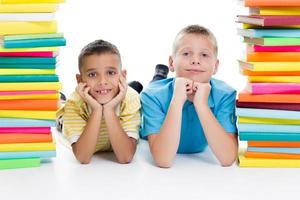 Students sitting behind pile of books on white background