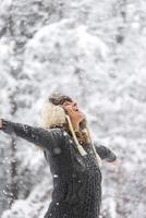 mujer feliz en la caída de nieve con los brazos abiertos