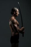 modelo masculino musculoso en estudio con una espada