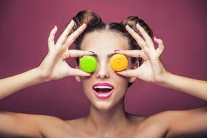 Model, a woman with bright make-up and colour biscuits joking. photo