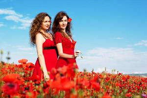 Two young women playing in poppies field photo