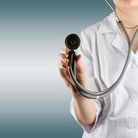 Female doctor's hand holding stethoscope on blurred background. photo