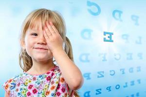 Little girl reading eye chart. photo