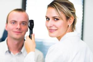 Optometry concept - pretty young woman having her eyes examined photo