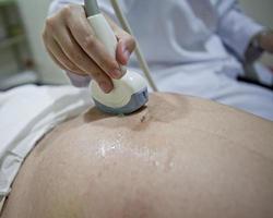 Obstetra examinando el vientre embarazado por ecografía. foto