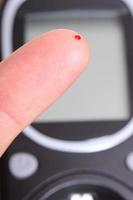 Closeup of finger with blood and glucose meter photo