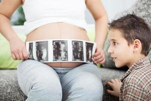 surprised boy looking at ultrasound image of their unborn brothe