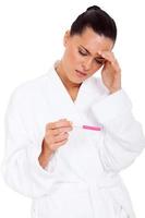 confused woman looking at pregnancy test result