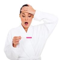 shocked woman in bathrobe with pregnancy test