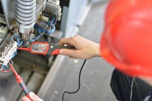 Electrician testing for voltage on terminal block