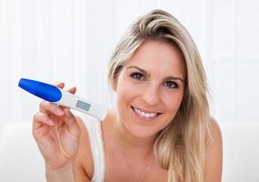 Happy woman looking  at positive pregnancy test
