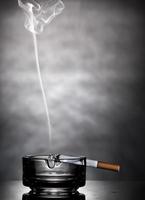 cigarrillo encendido en cenicero de vidrio foto
