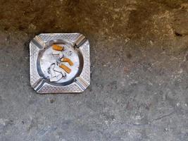 metal ashtray with cigarette stubs in closeup