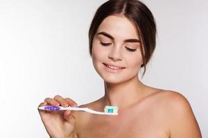 Teen girl is holding brush with toothpaste