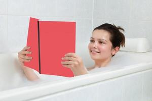 mujer joven en bañera leyendo libro foto