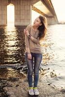 Young sensual woman standing on the stone near water photo