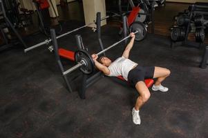 young man doing bench press workout in gym photo