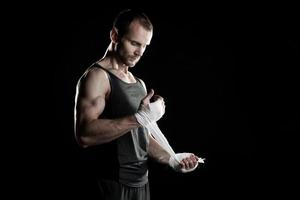 muscular man, tying an elastic bandage on his hand, black photo