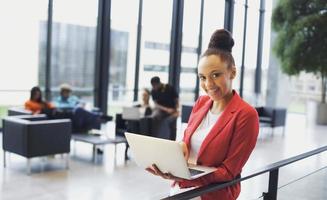 Beautiful young african woman with laptop in modern office photo