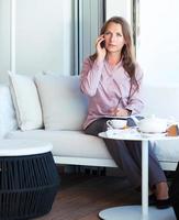 mujer de negocios hablando por teléfono celular en una cafetería foto
