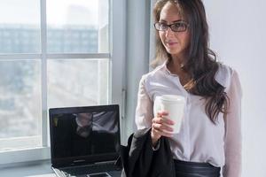 young woman in glasses with the cup of coffee or photo